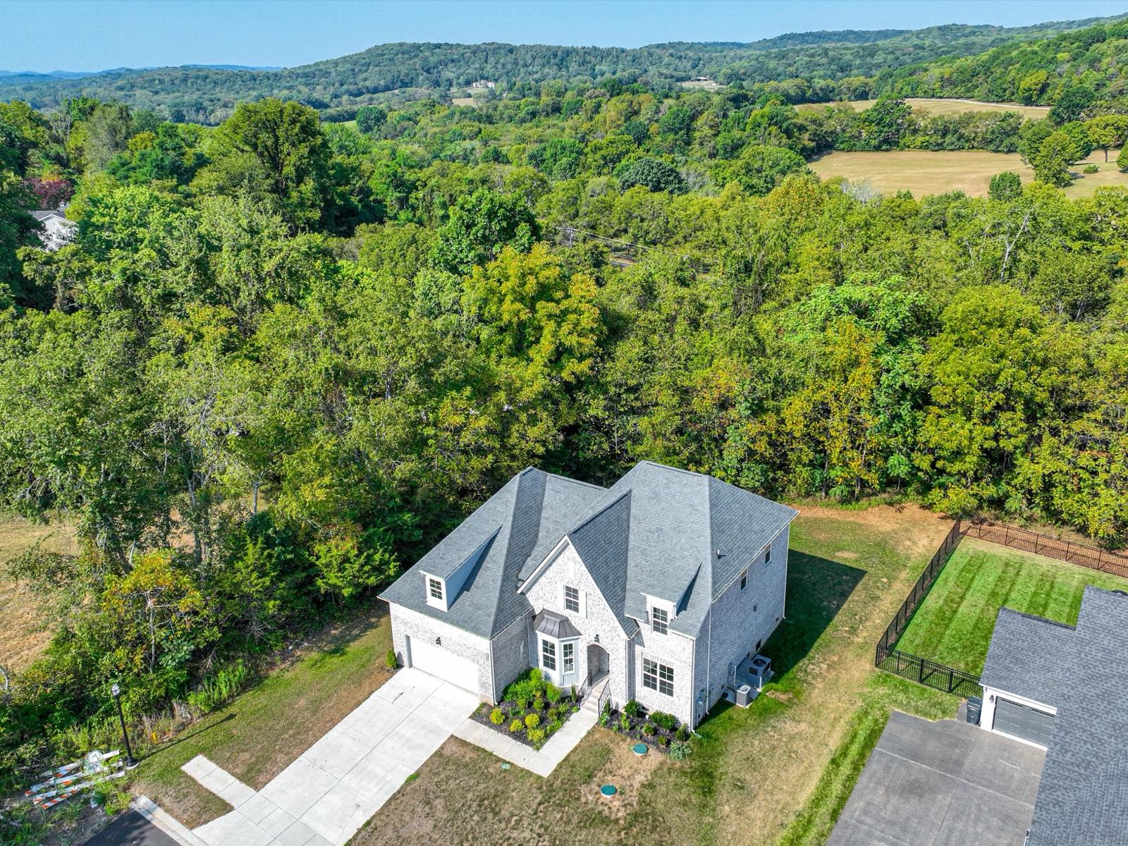 Aerial view of the lot at the edge of the neighborhood, woods and rolling hills beyond at 631 Silva Lane