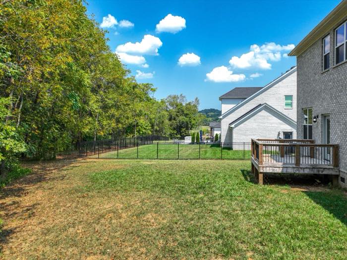 Fenced rear yard with woods on two sides